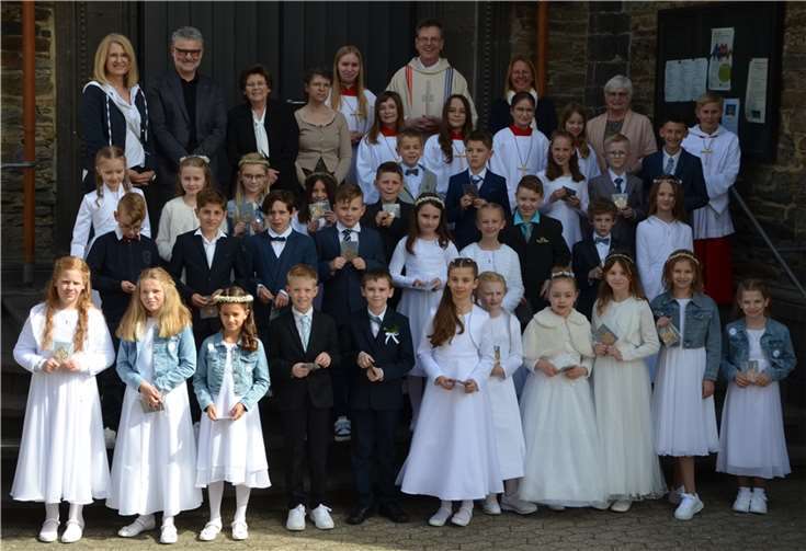 Pfarrei feiert Erstkommunion Kommunionkinder, Ministranten, die Katechetinnen Sabine Lohner, Nicki Meister und Evi Weinand, Pfarreienratsmitglieder Monika Leinz, Monika Bermel und Wolfgang Weber und Pastor Norbert Missong vor der Pfarrkirche Sankt Arnulf. Foto: Birgit Busenkell