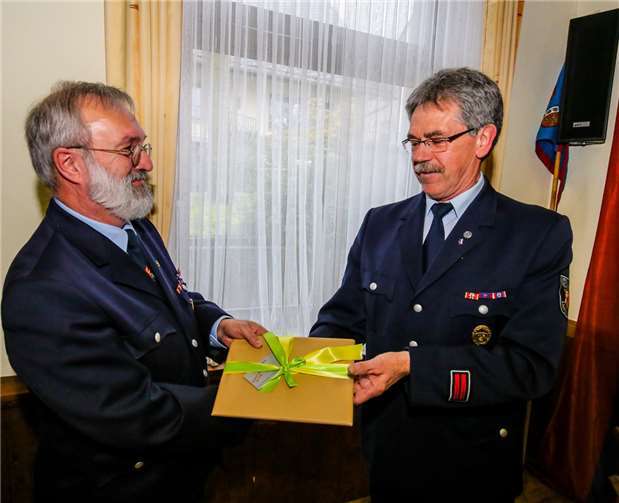 Kreisjugendfeuerwehrwart Horst Klee (r.), der die Laudatio hielt, überreichte Geschenke, die der „kommenden Langeweile“ entgegenwirken sollen.  