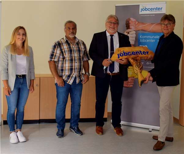 „Ich bin im Paradies“ Künstler Mo T. (2.v.li.) aus Mayen dankt mit einer Holzskulptur dem Jobcenter MYK für die Unterstützung bei seiner Integration in Deutschland. Burkhard Nauroth und Rolf Koch nehmen die kunstvolle Schnitzerei stellvertretend für alle Mitarbeiter entgegen.Foto: Landkreis Mayen-Koblenz