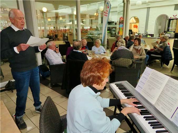 Kurt Gilles im Gesang und Arngard Schmidt bei der Präsentation eines Weihnachtsliedes auf der elektronischen Orgel mit den singenden Gästen im Hintergrund an den Tischen des Bistro-Restaurants der Römer-Thermen in Bad Breisig.  Foto: Rolf Niemeyer