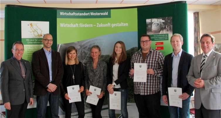 Landrat Achim Schwickert (r.) und WFG-Geschäftsführer Wilfried Noll (l.) übergeben im Beisein des Projektleiters Robert Kebbekus (2. v. l.) den Studierenden Karina Oberdörfer, Louisa Petrack, Sarah Eling, Michael Backfisch sowie Hannes Wehrmann die Zertifikate für die erfolgreich abgeschlossene Arbeit.