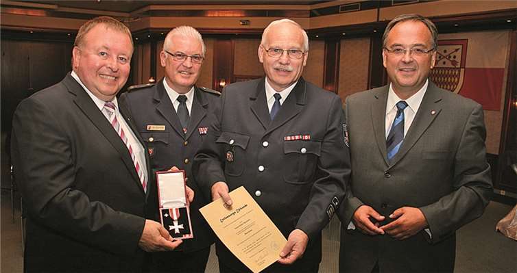 Landrat Dr. Jürgen Pföhler (li.) zeichnete gemeinsam mit Kreisfeuerwehrinspekteur Udo Schumacher den bisherigen Wehrleiter Hans-Dieter Baunach mit dem Goldenen Feuerwehrehrenzeichen am Bande aus, worüber sich auch Bürgermeister Bernd Weidenbach (re.) freute.
