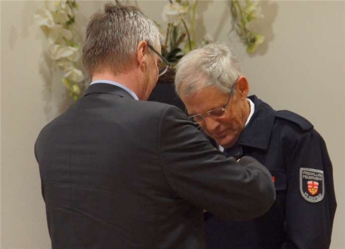 Landrat Dr. Saftig heftet Klaus Josef Adams aus Münstermaifeld das Goldene Feuerwehr-Ehrenzeichen an.