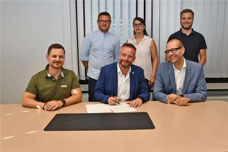 Landrat Marko Boos (vorne Mitte) und Prof. Dr. Wolfgang Kiess (vorne rechts) von der Hochschule Koblenz unterzeichneten den Vertrag zum Projekt RIOT im Beisein von Tobias Querbach (vorne links), CDO des Landkreises Mayen-Koblenz, der Projektmanagerin Tahmineh Bahadorizadeh (hinten Mitte) und weiteren Projektbeteiligten. Foto: Kreisverwaltung MYK/Wiebke Schaaf