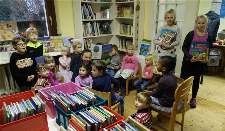 Leonie, Nora und Gunilla (stehend) mit ihren ausgesuchten Weihnachtsbüchern und die gespannten Kindergartenkinder in der Kinderbücherei. privat