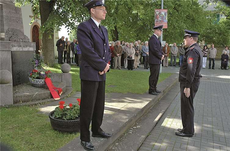 Löschgruppenführer Christian Klein stellt Blumen am Ehrenmal ab.