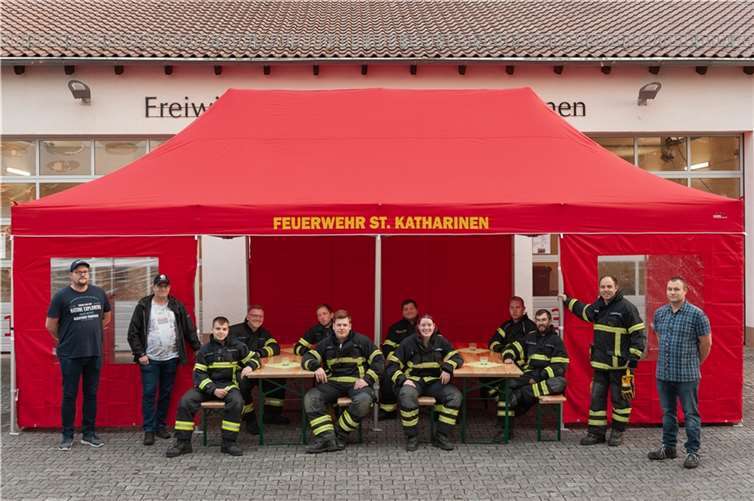 M. Homscheid, S. Feesenmeyer (beide Vorstand Förderverein), Aktive der Freiwilligen Feuerwehr St. Katharinen in Schutzkleidung; Wehrführer T. Schaarschmidt (stehend) sowie der Vorsitzende des Fördervereins J. Schlemmer bei der Übergabe des Zeltes (v.l.).Foto: FF St. Katharinen