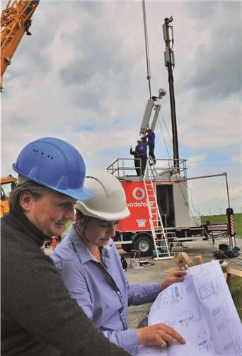 MRT-Projektleiter Timo Gnass von dem Hochtechnikunternehmen „Schlosserei Schwan“ (l.) und Susanne Taufertshöfer (Projektleiterin Mobilfunk Vodafone) verfolgen gespannt die Montage des Antennenkopfes auf dem MRT (Mobile Radio Trailer). FRE