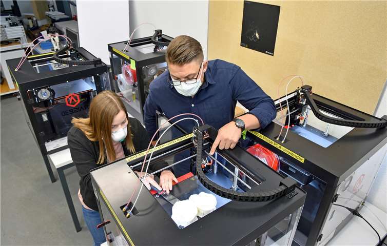 Maike Krämer und Maximilian Köthe entnehmen die Mund-Nasen-Masken aus dem 3D-Drucker. Fotos: Hochschule Koblenz