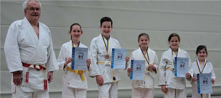 Mara Kremer, Simon Trefflich, Nele Ohly, Amira Trefflich und Karlotta Kremer (v. li.) sowie Moritz Jacoby (nicht im Bild) haben sich vorbildlich für Großmeister Ernst Elenz (6. Dan, rot-weißer Gürtel) bei der Katameisterschaft eingebracht. Foto: privat