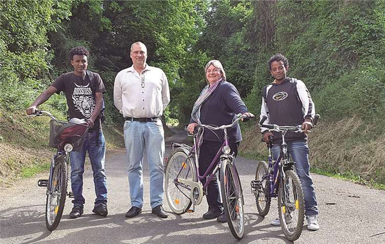 Maria Müller und Egmond Eich bei der Spendenübergabe in Unkelbach mit den jungen Männern, die sich über die funktionstüchtigen Fahrräder und hochwertigen Rucksäcke freuen.privat
