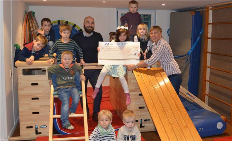 Mark Palmersheim von der Raiffeisenbank Voreifel und Kindergartenleiterin Susanne Krause freuen sich mit den Zaunkönigen über die Eröffnung des neuen Sport- und Toberaums.Foto: privat
