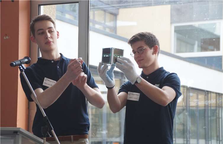Max v. Wolff (l.) und Peter Stein präsentierten dem interessierten Publikum den Kleinsatelliten, der Mayen vielleicht schon bald mit dem All verbinden wird.