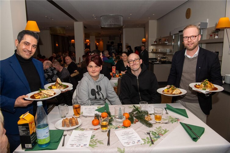 Mehran Davoudi, CEO UNICSNACKS (links) und Jan-Erik Burkard, Leiter Unternehmenskommunikation der VR Bank RheinAhrEifel eG (rechts) unterstützen tatkräftig bei dem Servieren des Weihnachtsmenüs. Foto: Peter Seydel