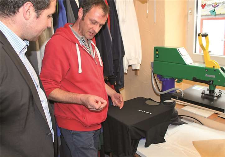 Michael Lenarzt von der Firma Stickmichel zeigt Benedikt Oster, worauf es beim Textildruck ankommt.