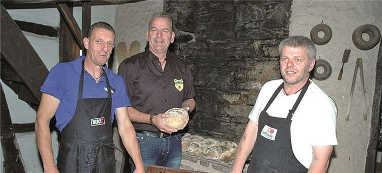 Michael Schwall, Ortsbürgermeister Marco Jax und Bruno Kratz holten das Steinofenbrot aus dem Ofen.