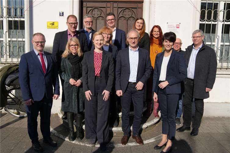 Ministerin Dörte Schall (vorne, 3.v.l.) und die Landtagsabgeordnete Lana Horstmann (2.v.l.) ließen sich bei ihrem Besuch der Caritas von beteiligten Neuwieder Akteuren um OB Jan Einig (vorne links), Jobcenter-Geschäftsführer Theo Krayer (vorne, 2.v.r.), Arbeitsagentur-Chefin Stefanie Adam (vorne rechts), 1. Kreisbeigeordneter Philipp Rasbach (hinten links), Caritas-Direktor Eberhard Köhler (hinten, 2.v.l.) Bürgermeister Peter Jung (hinten Mitte) und Helmut Hecking als Vertreter der Wirtgen-Stiftungen (hinten, 2.v.r.) das Housing First-Projekt vorstellen, das in der Deichstadt seit über drei Jahren erfolgreich praktiziert wird.  Foto: Lena Geisler