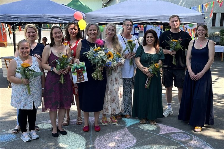 Miriam Niederehe (2.v.l.), stellvertretende Geschäftsführerin von Betreute Schulen e.V., und die zuständige Fachbereichsleitung, Melanie Weingartz (1.v.r.), bedankten sich mit Blumen bei OGS-Leitung Martina Neckel (5.v.l.) und ihrem Team.