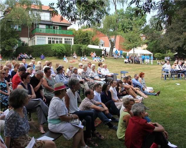 Mit Festival-Flair feiern rund 220 Gäste den Jubiläumsgottesdienst auf Bänken, Kissen oder einfach im Gras sitzend. Dorothea Mueth