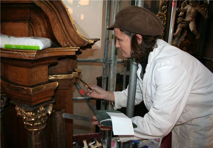 Mit Hilfe eines Vergolderkissens und eines Vergoldermessers schneidet Katrin Etringer das Blattgold zu, bevor sie es an der Oberfläche aufbringt.