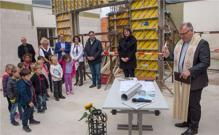 Mit Weihwasser von Pfarrer Michael Hoßdorf gesegnet wurde die Dinge, die künftig im Grundstein des Erweiterungsbaus des Kindergartens Berkum ihren Platz haben werden. Fotos: JOST
