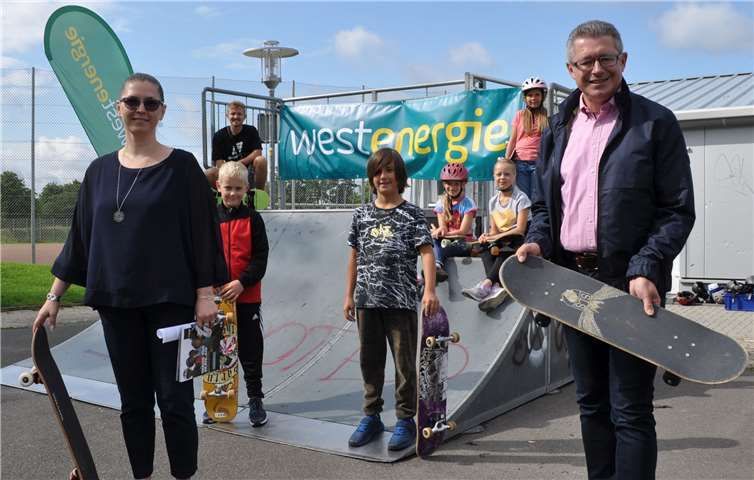 Mit dem Board an der Skateranlage: der Erste Beigeordnete Hans Dieter Wirtz (rechts), die Fachbereichsleiterin Anna Sitner (links), Fiete Kunigk von der RheinFlanke (hinten knieend) und einige der insgesamt 31. teilnehmenden Kinder. Foto: Stadt Meckenheim