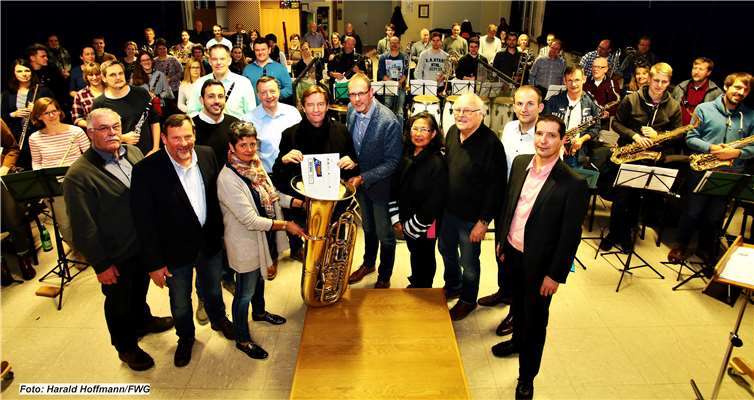 Mit dem Dirigenten Bertram Klei zu seiner linken und dem 1. Vorsitzenden des Stadtorchesters Volker Montermann zu seiner rechten verstaut FWG-Vorsitzender Egon Schäfer (Bildmitte) den Spendenscheck sicher in einer Tuba. Foto: Harald Hoffmann