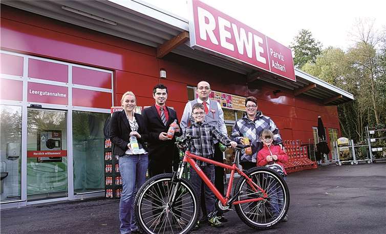 Mit dem glücklichen Sieger Kai Hengsberg (Mitte am Fahrrad) freuen sich seine Mutter Silke und Schwester Lara (re.), Georg Wolf von REWE (Mitte hinten) und Astrid Lettau und Andreas Wiesner (li.) vom Sinziger Brunnen.RÜ