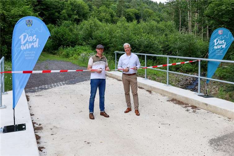 Mit dem symbolischen Akt der Durchschneidung des Absperrbandes gaben Ortsbürgermeister Benedikt Knoche (li.) und Dominik Gieler, Bürgermeister der Verbandsgemeinde Altenahr, die Vischelbachbrücke in Berg offiziell frei.Foto: Thorsten Trütgen / VG Altenahr