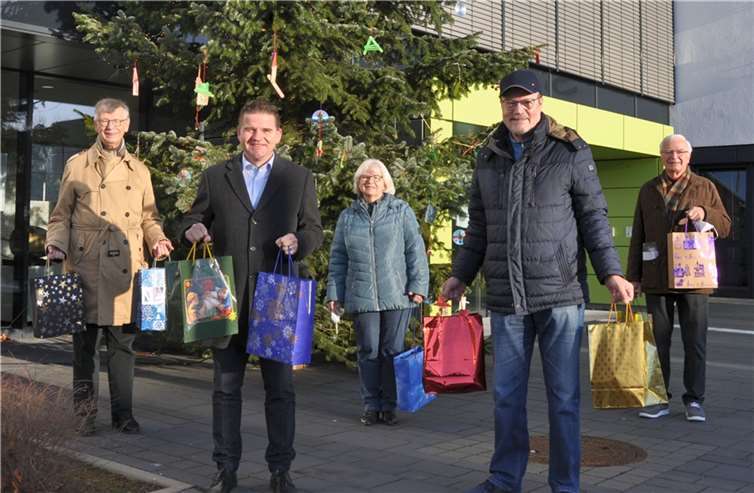 Mit den Geschenktüten vor dem Weihnachtsbaum am Rathaus, von links: Manfred Weizbauer, Lions-Club, Bürgermeister Holger Jung, die städtische Demografiebeauftragte Bettina Hihn, Michael F. Firmenich, Präsident des Lions-Clubs, und Joachim Krüger vom Lions-Club. Quelle: Stadt Meckenheim