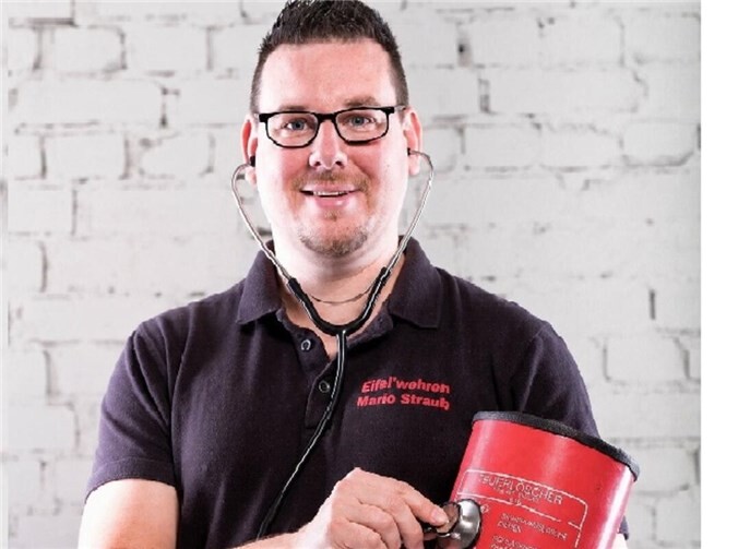Mit einem Augenzwinkern für mehr Sicherheit: Mario Straub von den Eifel´wehren „hört“ einen Feuerlöscher mit dem Stethoskop ab. Die humorvolle Aktion soll auf die regelmäßige Prüfung von Feuerlöschern nach DIN 14406-4 aufmerksam machen.