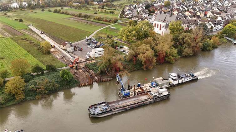 Mit einem Spezialbagger, der auf einem Ponton steht, schaffen die Arbeiter Platz für die neue Trinkwasserleitung. Auf Niederwerth ist zudem das bereits vorbereitete 180 Meter lange Rohrsystem zu erkennen, das auf den Feldern liegt.  Foto: Sascha Ditscher/evm