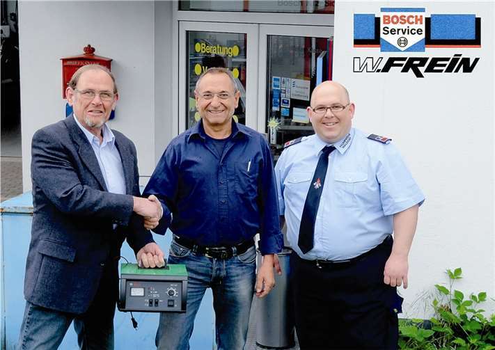 Mit einem herzlichen Dank nahm Norbert Cremer (l.), der 2. Vorsitzende des Fördervereins, im Beisein von Wehrführer Sascha Cremer (r.) von Firmeninhaber Wolfgang Frein das neue Ladegerät entgegen. WK