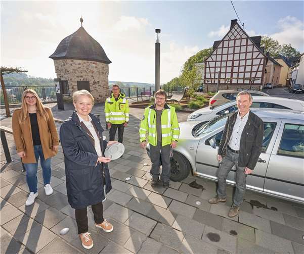Mit kluger Technik zu weniger Emissionen: Sarah Hermes und Norbert Rausch, beide evm, haben im Beisein von Stadtbürgermeisterin Gabi Wieland und den Mitarbeitern Sven Müller und Mathias Lau, den Bodensensor auf dem Karoline-Kahn-Platz montiert.Foto: evm/Ditscher