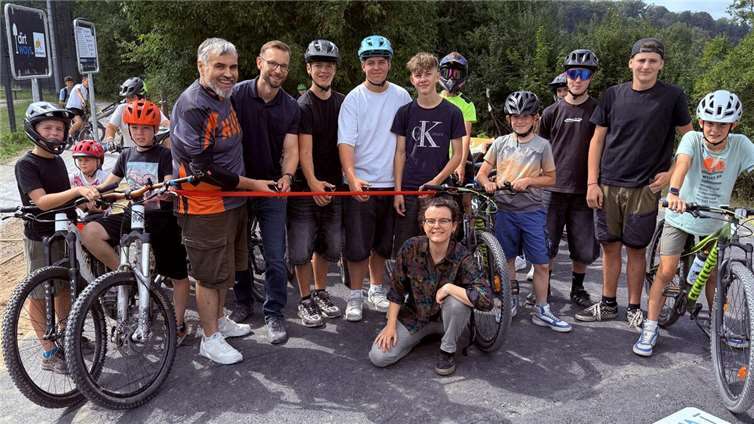Jugendprojekt wird Realität: Pumptrack in Montabaur eröffnet  Mit vereinten Kräften durchs rote Band: Sascha Kniel (links), Beigeordneter der Stadt Montabaur, VG-Bürgermeister Ulrich Richter-Hopprich (2.v.l.) und Projektleiterin Larissa Metz (kniend) eröffneten gemeinsam mit den Jugendlichen den neuen Pumptrack in Elgendorf.  Fotos: VG Montabaur/Holger Pöritzsch