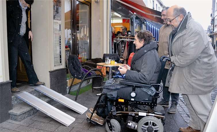 Mit vereinten Kräften und auf zusammenklappbaren Rampen wird der Rollstuhl ins Lieblingscafé geschoben. WM