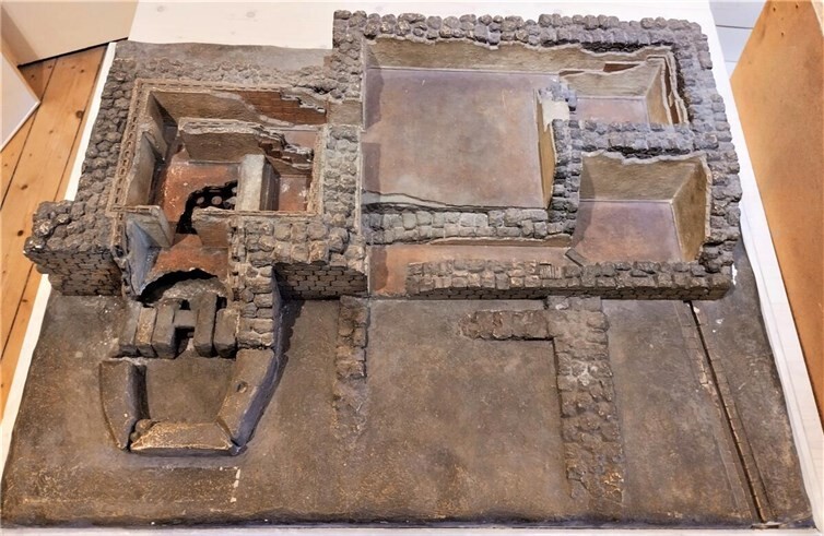 Modell des römischen Bades der Villa am Marienstätter Hof. Links das Warmbad (Caldarium) mit der Heizanlage („Praefurnium“ = Ofen und „Hypocaust“ = Fußboden-/Wandheizung), vorne rechts die Wasserrinne zum Deubach.  Foto: Stadtmuseum Andernach.
