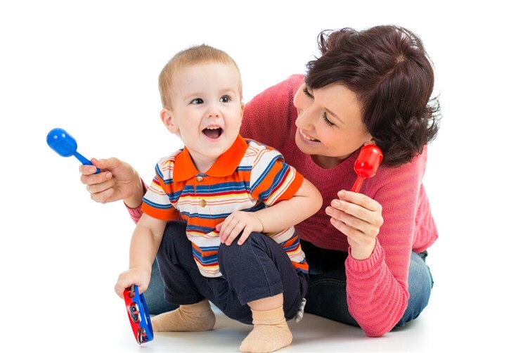 Mother and baby boy having fun with musical toys. Isolated on white background