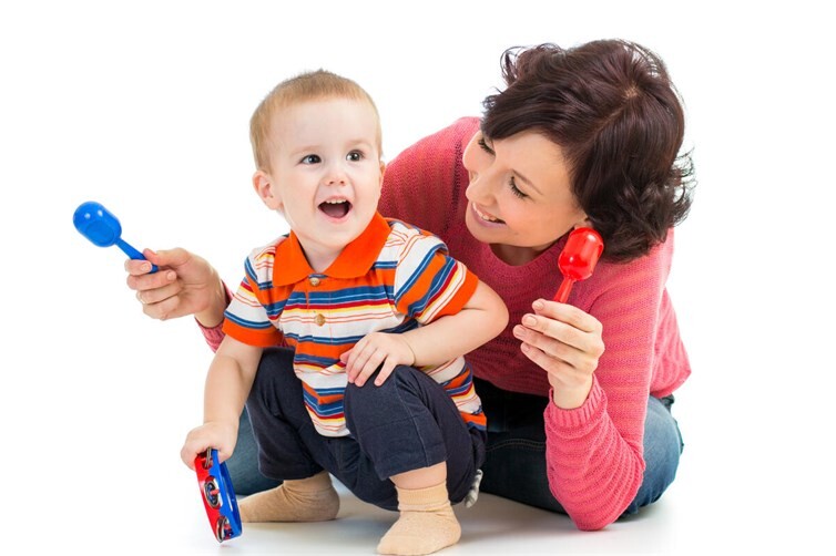 Mother and baby boy having fun with musical toys. Isolated on white background