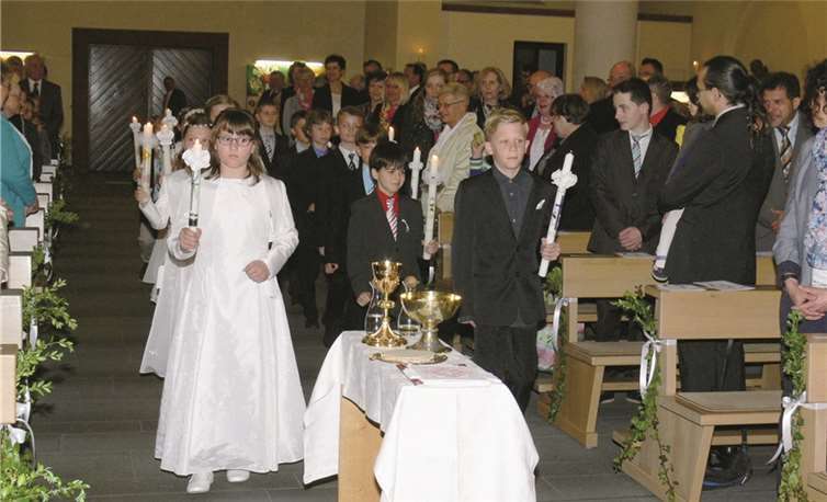 Nach dem Entzünden ihrer Kommunionkerzen schritten die Kinder in Begleitung von Pastor Markus Arndt in den Chorraum der Kirche. TE