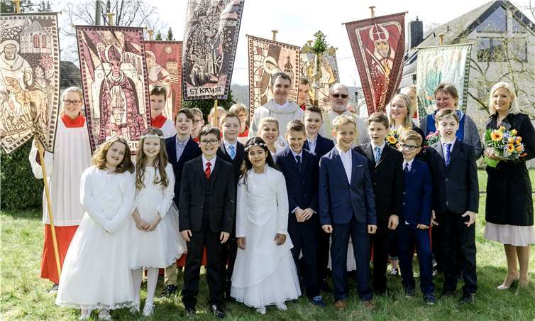Nach ihrer ersten Teilnahme am Abendmahl stellten sich die 13 Unkeler Erstkommunionkinder zusammen mit Pfarrer Andreas Arend, Diakon Winfried Reers, den Messdiener und mit ihren drei Katechetinnen im Pfarrgarten zum Gruppenbild auf. DL