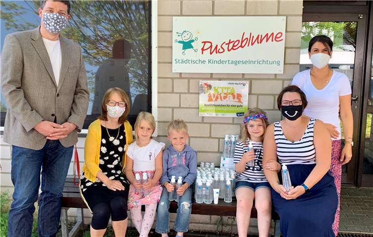 Nachschub für die Hygiene: Renate Schliebach (sitzend links) nahm gemeinsam mit Kindern und Erzieherinnen der Kita Pusteblume das von Sebastian Groß (stehend links) überreichte Spendenpaket entgegen. Foto: Stadt Meckenheim