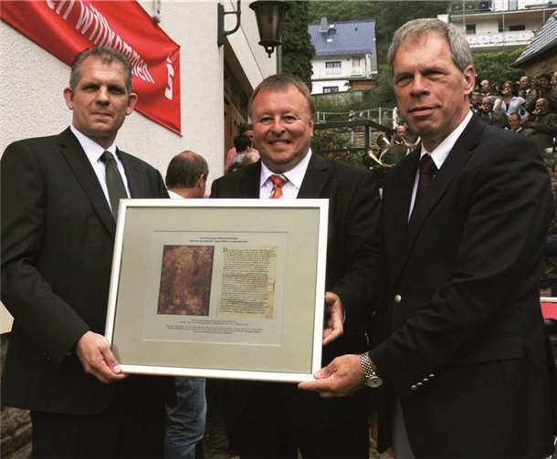 Neben der Reproduktion der Urkunden-Abschrift aus dem Goldenen Buch von Prüm, die Landrat Pföhler (Mitte) an Ortsbürgermeister Kai Köpcke (l.) überreichte, stiftete er noch einen Baum. Achim Haag (r.). -SES-