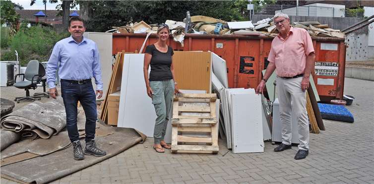Nehmen das Ausmaß des Hochwassers an der Evangelischen Grundschule in Augenschein, von links: Bürgermeister Holger Jung, Schulleiterin Julia Gahl und Landrat Sebastian Schuster vor einem Berg voller Unrat. Foto: Stadt Meckenheim