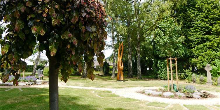 Neu angelegt wurde der Basaltgarten für Urnenbestattungen. Im Hintergrund ist die helle Holzskulptur der Künstlerin Simone Levy zu sehen. Sie trägt den Titel Kreislauf des Lebens: Die äußeren beiden Arme stellen den irdischen Körper dar, der innere, sich schlängelnde Teil die Seele, die durch den Tod die Freiheit gewinnt.