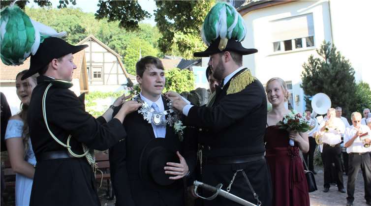 Niclas Richarz und Kilian Rechmann inthronisiertenTobias Gebauer am Dorfbrunnen mit der Königskette.