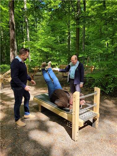 OB Lennart Siefert und Beigeordneter Sebastian Seifert testen unter Anleitung von Dr. Jörg Henning die Geräte im neu eröffneten Fitness-Parcours im Kur- und Heilwald Lahnstein.  Foto: Astrid Haderlein / Stadtverwaltung Lahnstein