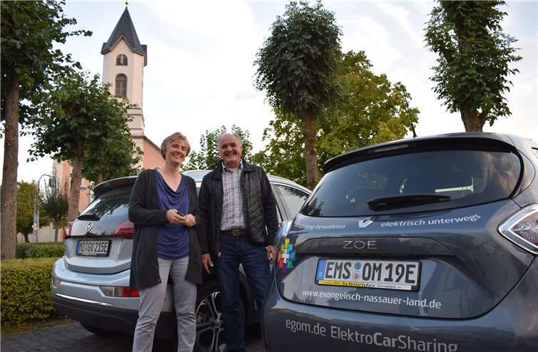 Ob das Autokennzeichen mit MZ oder EMS beginnt, beide enden mit einem E: Kathrin Saudhof vom Zentrum Gesellschaftliche Verantwortung in Mainz und Pfarrer Matthias Metzmacher aus Bad Ems kamen mit einem Elektro-Auto zum Infoabend in Singhofen, wo das Umweltmanagement-Zertifikat Grüner Hahn vorgestellt wurde.Foto: privat