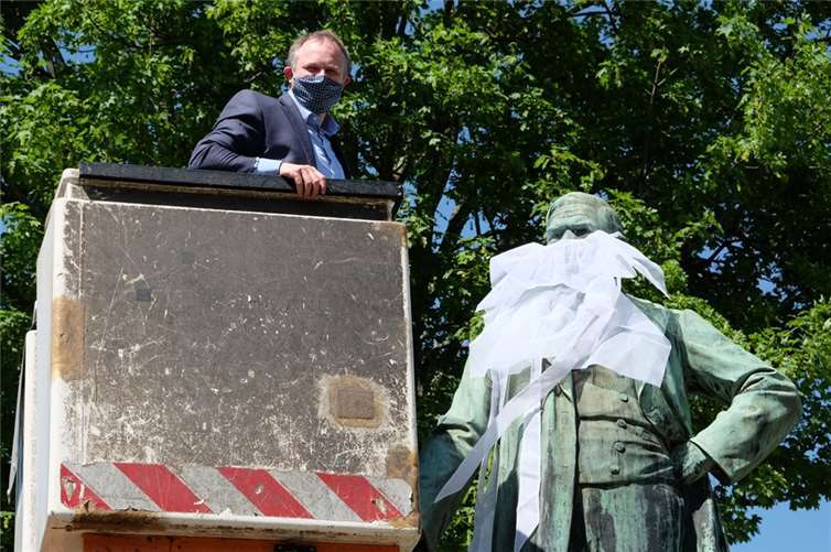 Oberbürgermeister Jan Einig legte selbst Hand an, um dem Raiffeisen-Denkmal einen Mund-Nasen-Schutz anzulegen.