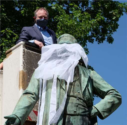Oberbürgermeister Jan Einig legte selbst Hand an, um dem Raiffeisen-Denkmal einen Mund-Nasen-Schutz anzulegen.